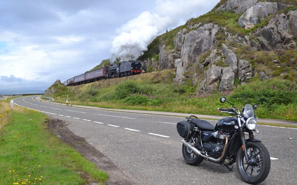 de street twin langs de weg met op de achtergrond de jacobite stoomtrein